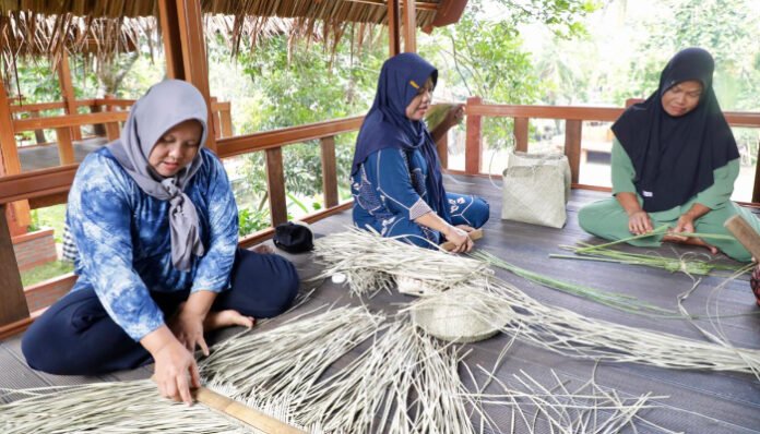 Para pengrajin sedang mengolah anyaman tradisional menjadi tas bernilai ekonomi.