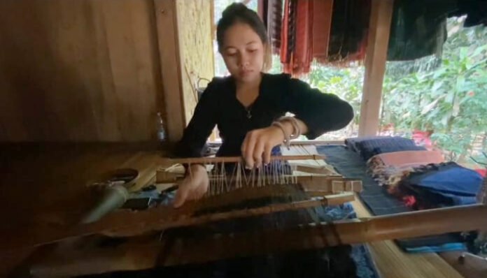 Seorang perempuan Baduy tengah menenun kain tradisional menggunakan alat tenun warisan leluhur di salah satu rumah panggung di Lebak, Banten.