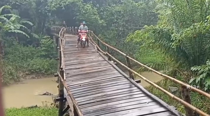 Warga Desa Cikeusik, termasuk para pelajar, harus melintasi jembatan miring yang membentang di atas Sungai Cikayang (Bantentv.com/ Rangga)