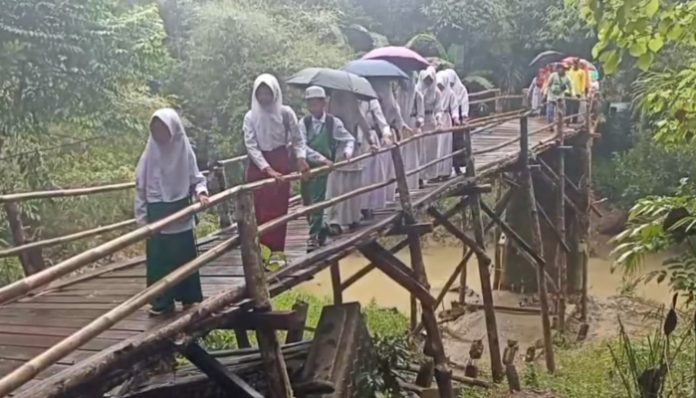 Para pelajar sedang melintasi jembatan Blengbeng, Cikeusik Pandeglang, yang sudah miring 20 derajat. (Foto: Bantentv.com)