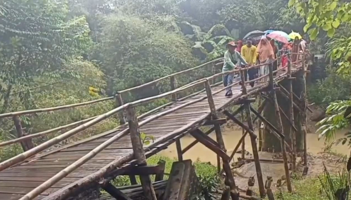 Sejumlah warga sedang melintasi jembatan Blengbeng, Cikeusik Pandeglang, yang sudah miring 20 derajat. (Foto: Bantentv.com)