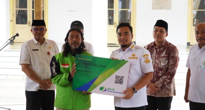 Robinsar secara simbolis memberikan jaminan sosial ketenagakerjaan kepada pekerja rentan (Bantentv.com/ Ali)