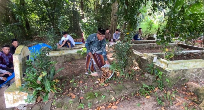 Seorang warga membersihkan makam keluarganya (Foto: Bantentv.com/ Imron)