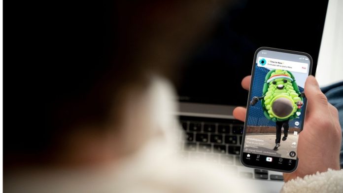 Ilustrasi seorang anak membuka aplikasi TikTok di ponsel