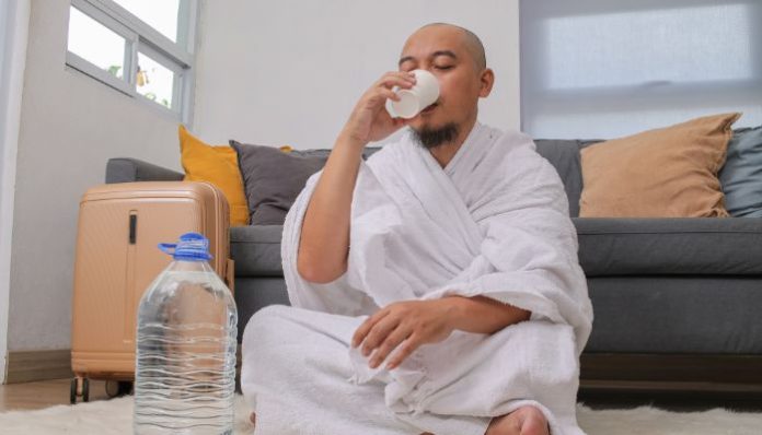 Ilustrasi. Seseorang tengah meminum air zamzam (Foto: Canva/ Garakta Studio)