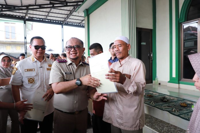 Kepala Kantor Pertanahan Kota Serang, Osman Affan tengah menyerahkan sertipikat PTSL kepada salah satu warga (Foto: Humas BPN Kota Serang)